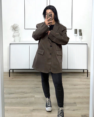 Blazer oversize marron à fines rayures blanches, coupe droite structurée avec épaules marquées, porté avec un jean noir et des baskets montantes.
