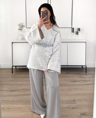 Veste kimono femme argentée et grise à motif brocart, coupe fluide avec manches larges et ceinture grise tressée, portée avec pantalon gris ample.