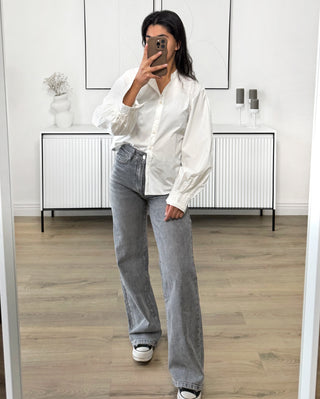 Chemise oversize à manches ballon, col classique et poignets boutonnés, portée avec un jean gris.